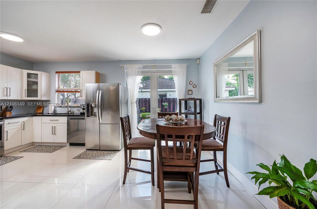 Kitchen featuring white cabinetry, stainless steel appliances, large-format tile flooring, and glass French doors