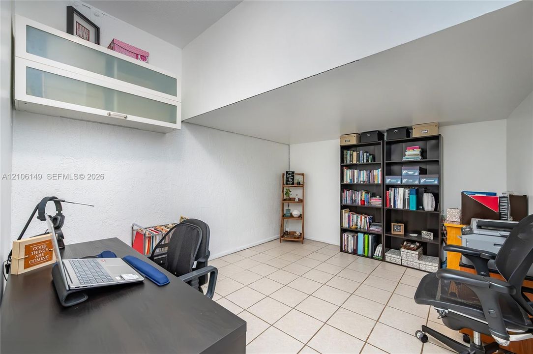 Room featuring neutral ceramic tile flooring and wall-mounted white cabinetry with frosted glass doors