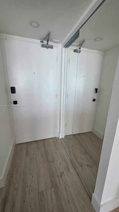 Entryway featuring wood-finish flooring, recessed lighting, and a mirrored sliding door closet