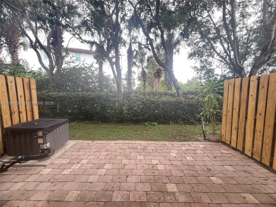 Paver patio featuring a fenced outdoor space, mature trees, and landscaping