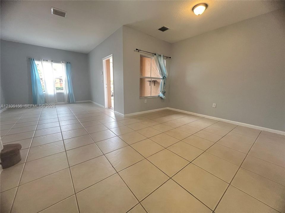 Interior space featuring light-toned tile flooring, neutral wall paint, and multiple windows providing natural light