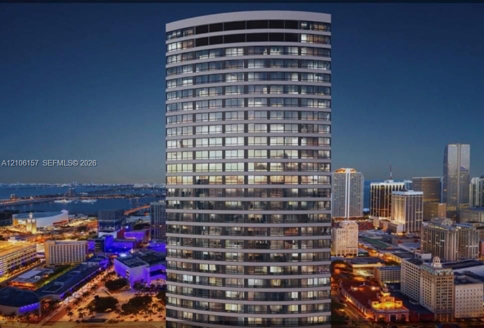 High-rise tower featuring a cylindrical glass facade, floor-to-ceiling windows, and private balconies