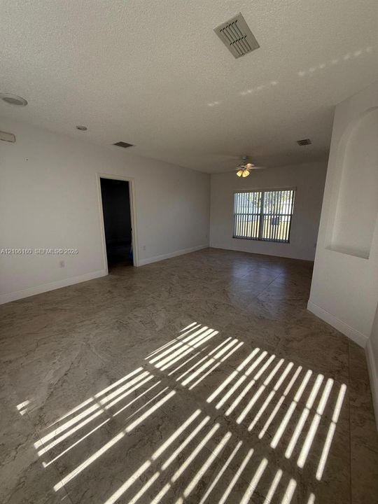 Open-concept interior featuring large-format tile flooring, recessed ceiling lighting, a ceiling fan with integrated light fixture, and an arched architectural wall niche