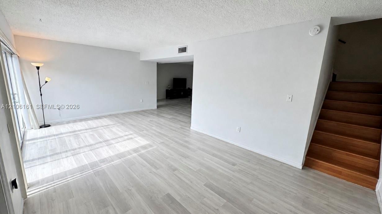 Open-concept floor plan featuring wood-finish flooring, staircase with wood treads, and sliding glass door