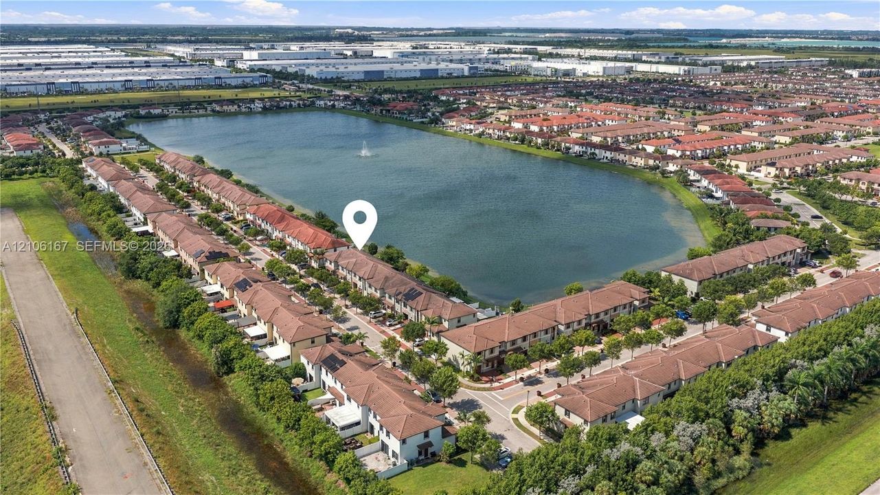 Aerial perspective of a multi-unit residential community featuring clay tile roofing and waterfront positioning along a central lake