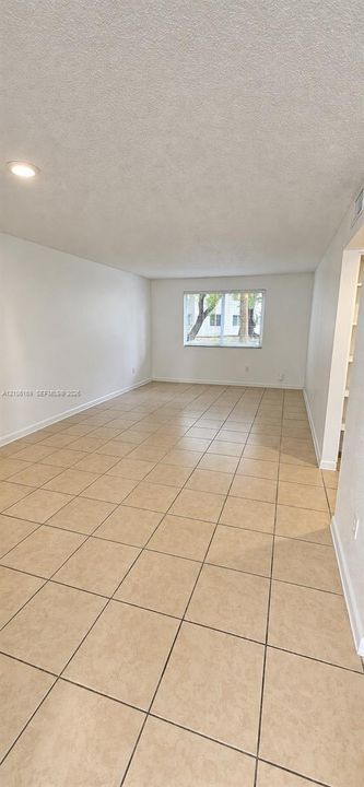 Open floor plan featuring neutral ceramic tile flooring, recessed lighting, and a window providing natural light