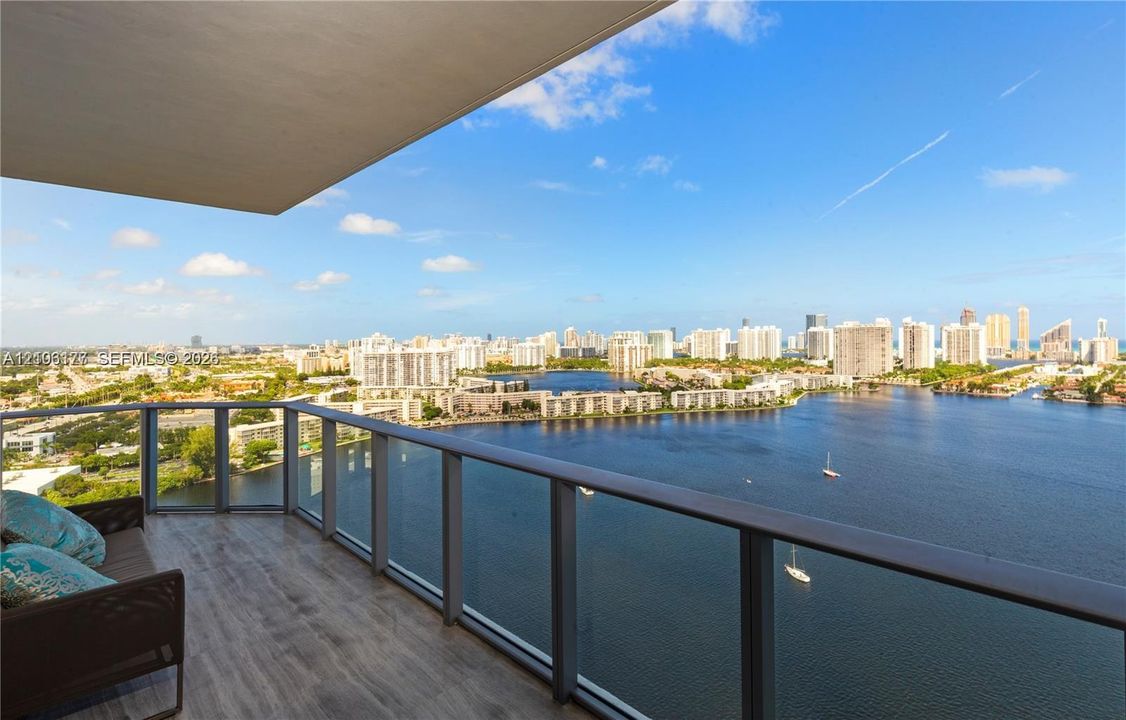 Covered balcony featuring wood-finish flooring and a glass railing with metal framing
