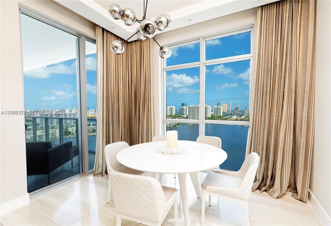 Floor-to-ceiling windows, polished stone flooring, recessed ceiling detailing, and a modern multi-globe chandelier