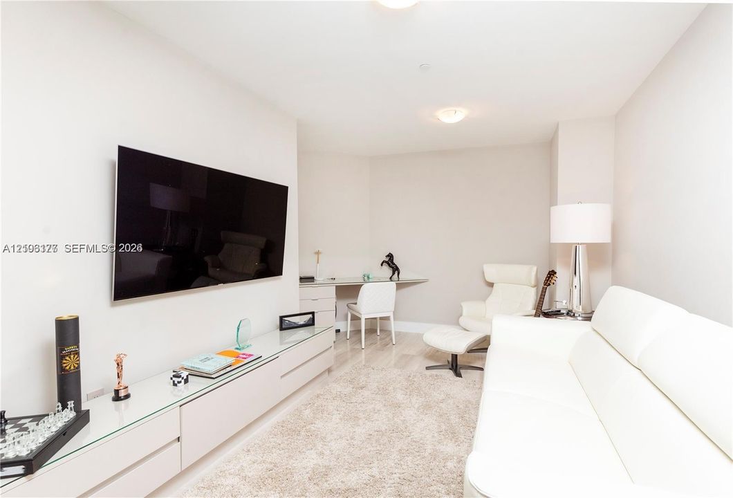 Room featuring neutral walls, light-toned wood-finish flooring, and a wall-mounted floating media console with a glass top