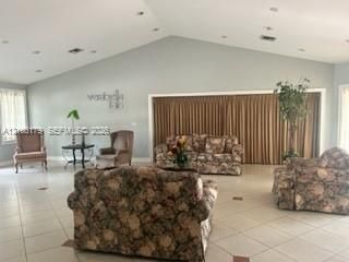 Vaulted ceiling with recessed lighting and neutral tile flooring