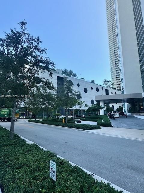 High-rise structure featuring a contemporary facade with circular architectural accents, a covered entrance, and manicured landscaping
