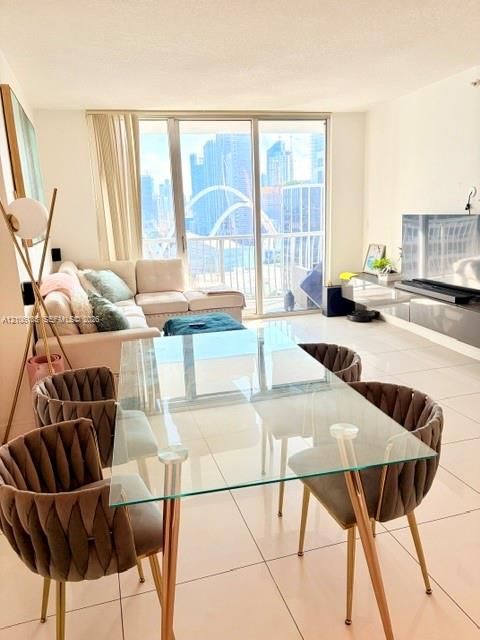 Living area featuring large-format tile flooring, wall-mounted cabinetry, and expansive floor-to-ceiling glass sliding doors opening to a balcony
