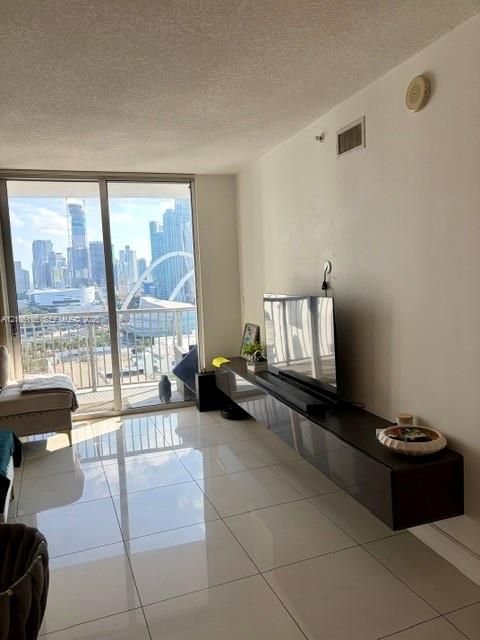 Floor-to-ceiling sliding glass doors opening to a private balcony, high-gloss tile flooring, and wall-mounted floating cabinetry