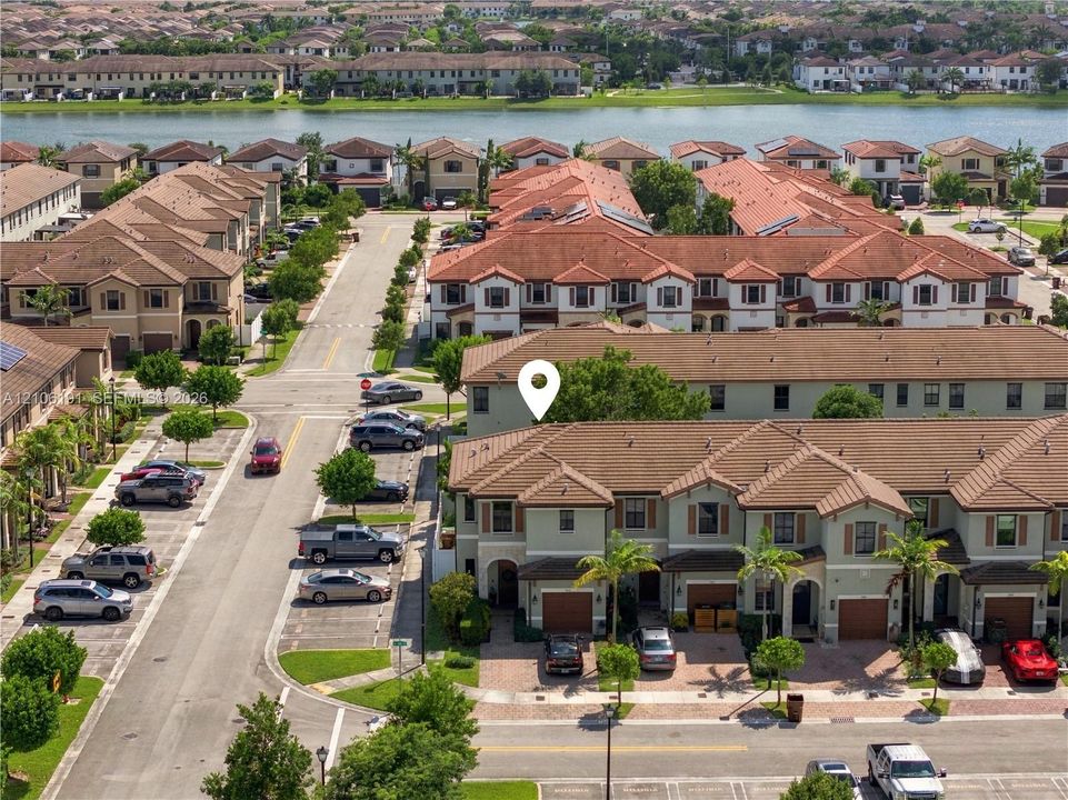 Multi-level townhome featuring a clay tile roof, stucco exterior, integrated garage, and brick-paver driveway