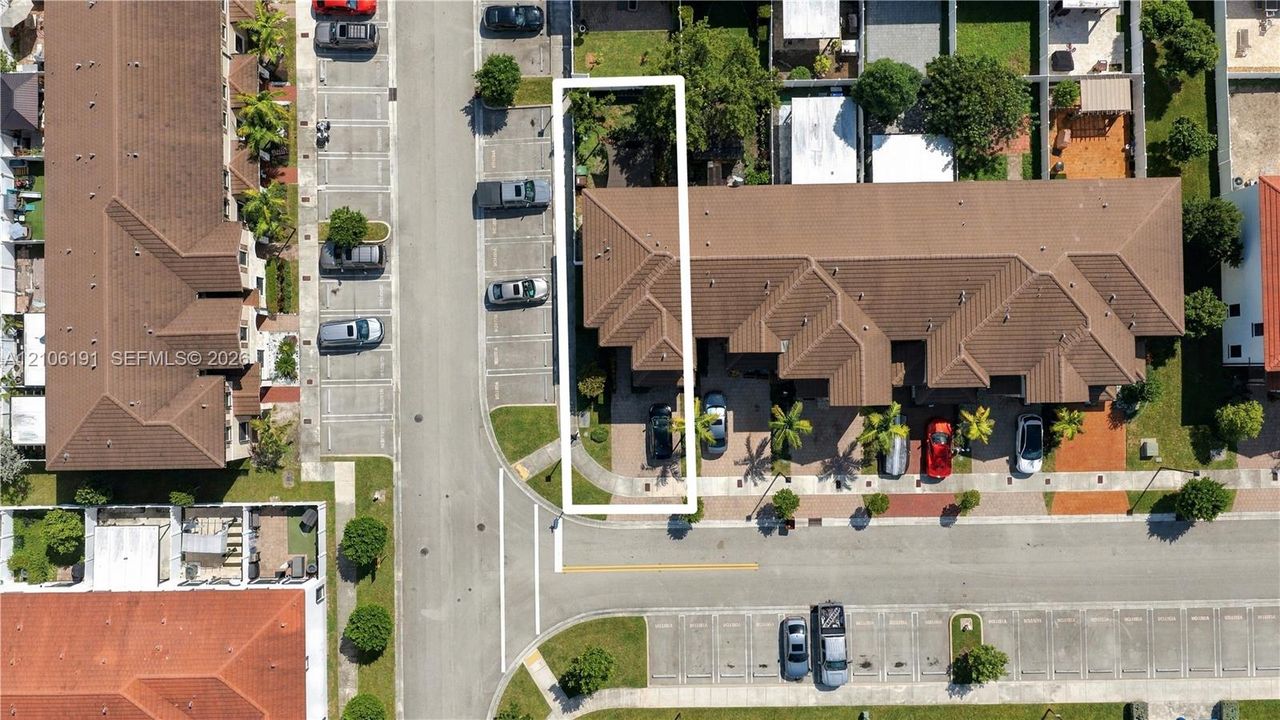 Aerial perspective highlighting a multi-unit property featuring a shingle roof, concrete driveway, attached parking, and established landscaping