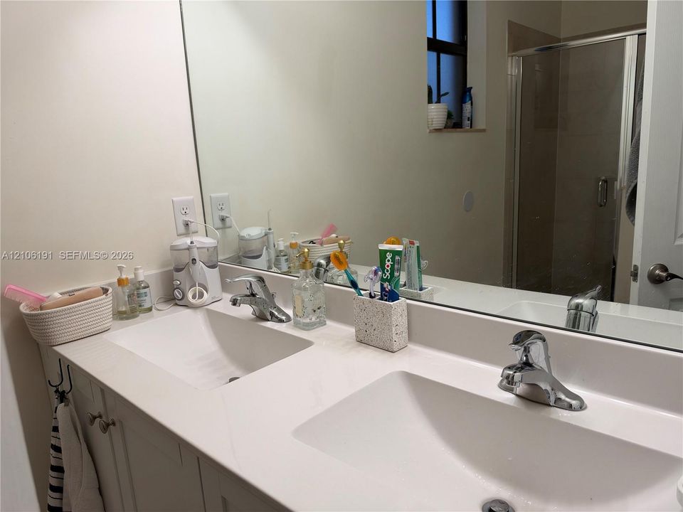 Dual-sink vanity with white countertop, integrated basin sinks, chrome faucets, and large wall-mounted mirror