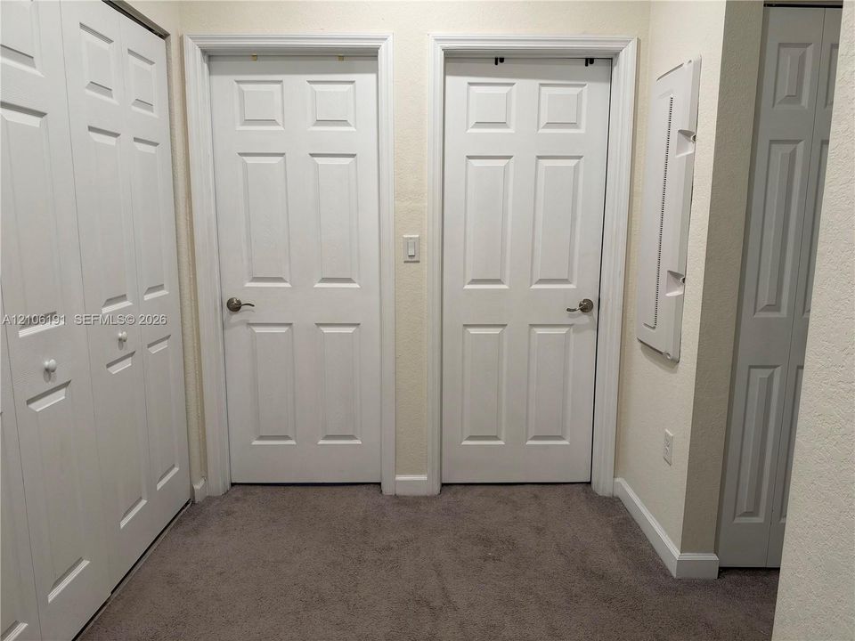 Interior space featuring neutral wall-to-wall carpeting, multiple six-panel interior doors, and built-in closet storage with bi-fold doors
