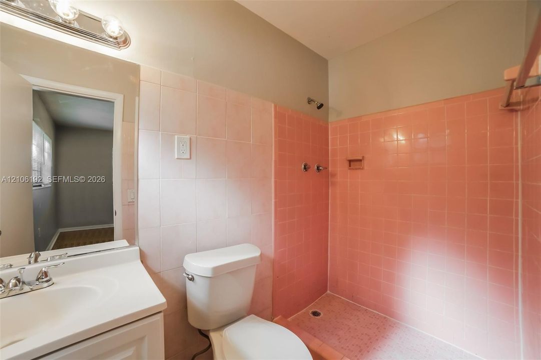 Bathroom featuring ceramic wall tiling, white vanity with integrated sink, chrome-finished hardware, and walk-in shower enclosure