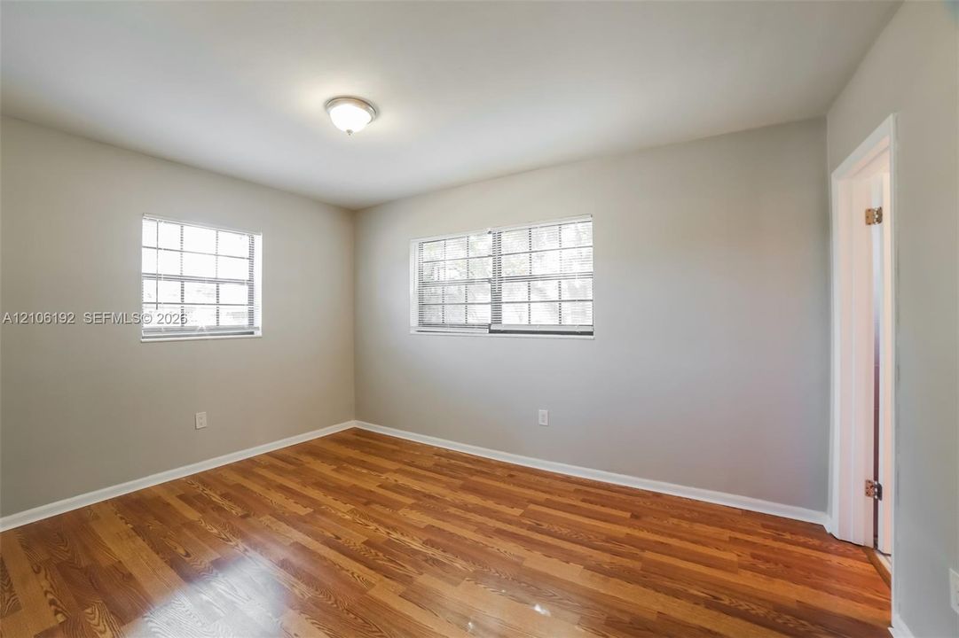 Room featuring wood-finish flooring, neutral wall paint, multi-pane windows, and a flush-mount ceiling light fixture