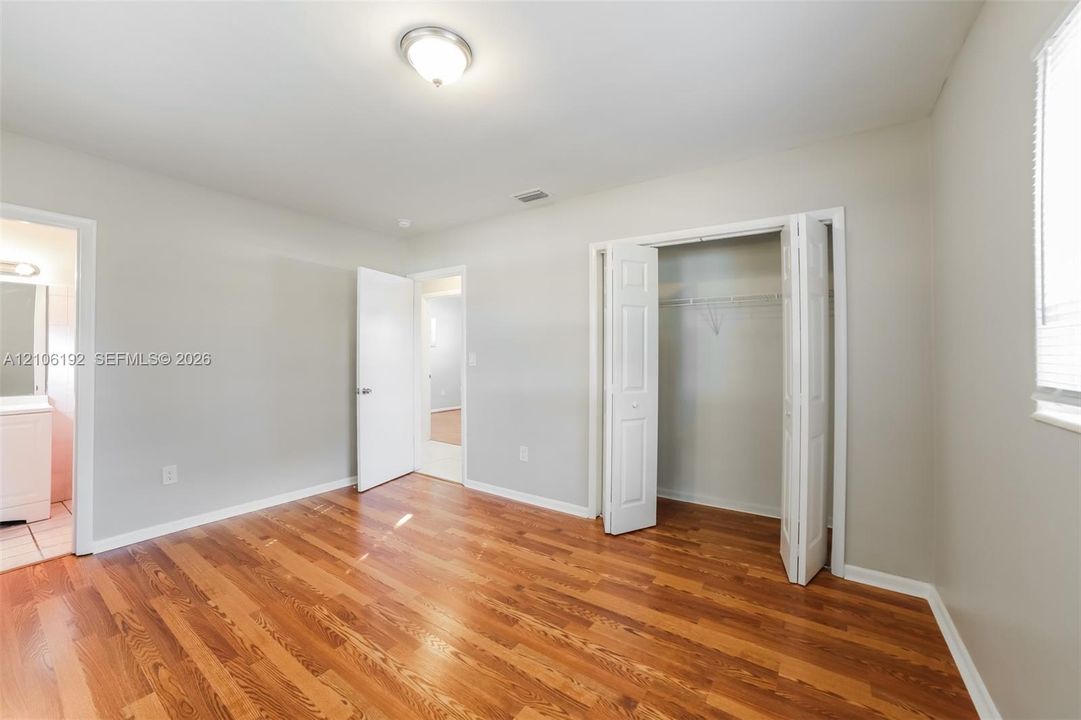 Interior space featuring wood-finish flooring, neutral wall paint, and a built-in closet with double-panel doors