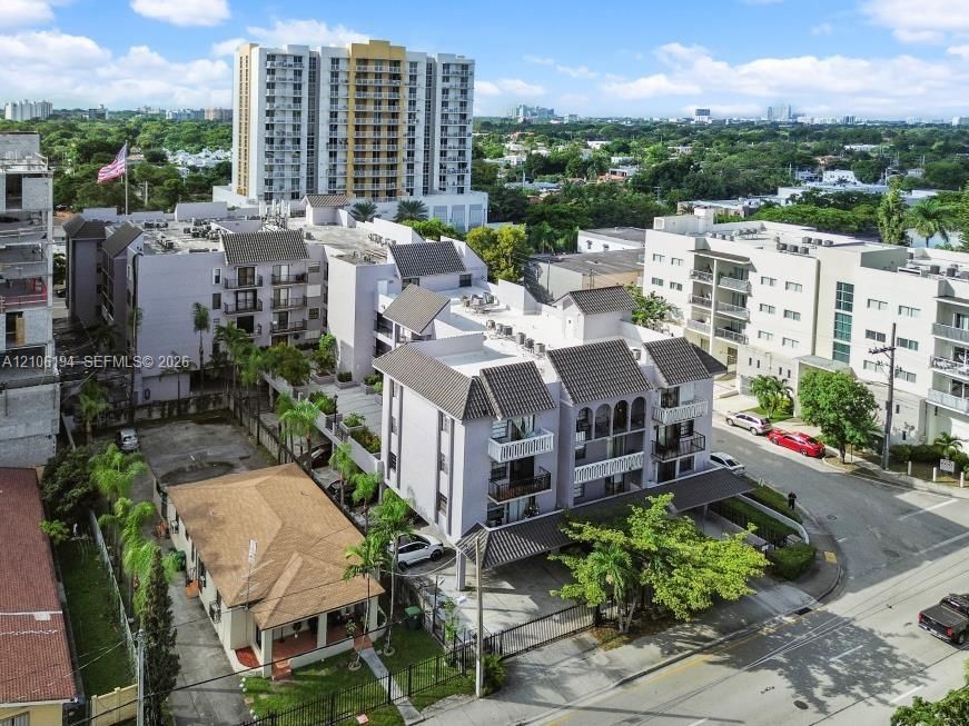 Aerial perspective of a multi-story residential building featuring covered parking, gabled rooflines, decorative arched trim, and gated perimeter access
