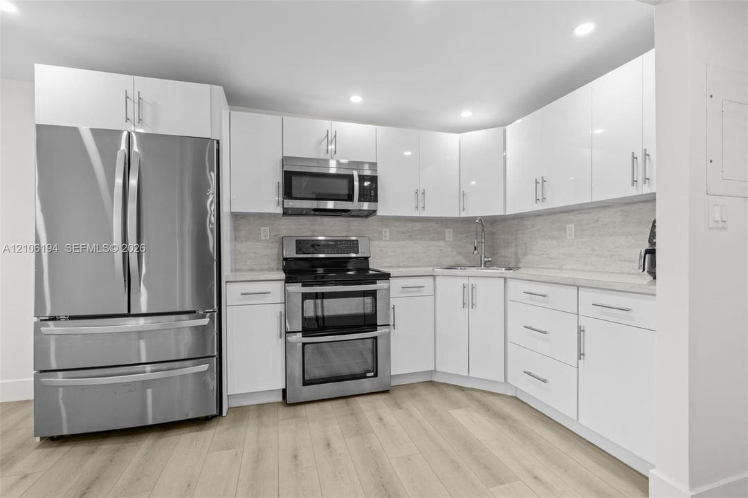 Kitchen featuring white high-gloss cabinetry, stainless steel appliances, and recessed lighting