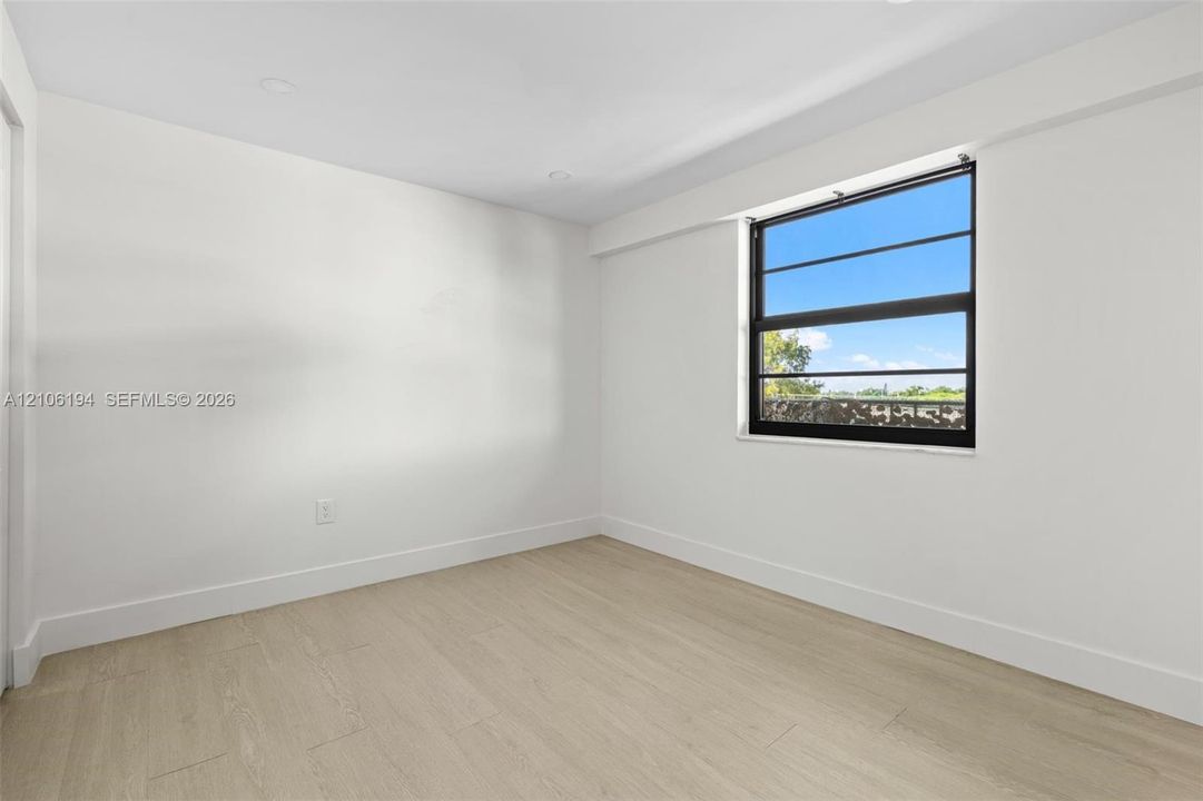 Neutral-toned interior space featuring  recessed lighting, and a single-hung window with a black frame