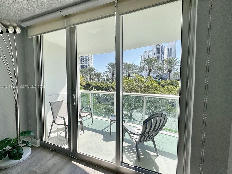 Full-height sliding glass doors with aluminum frames opening to a balcony featuring a glass-paneled railing
