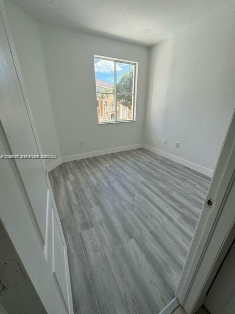 Room featuring neutral-toned walls, wood-finish flooring, and a single-pane window