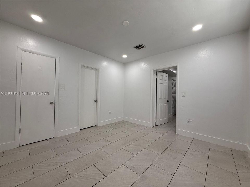 Interior space featuring recessed lighting, smooth-finish walls, and neutral-toned rectangular tile flooring