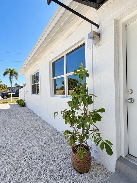 Stucco exterior featuring dual-pane windows, a metal door with brushed nickel hardware, and a minimalist wall-mounted outdoor light fixture