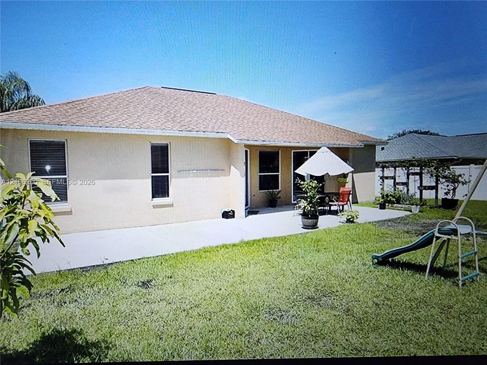 Stucco exterior with a hip roof, concrete patio, and fenced backyard