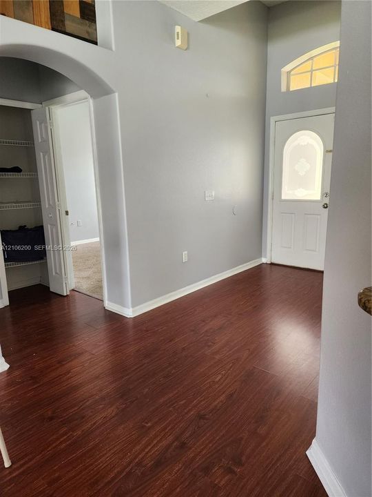 Entryway featuring wood-finish flooring, high ceilings, an arched entry, a door with a decorative glass insert, and a transom window