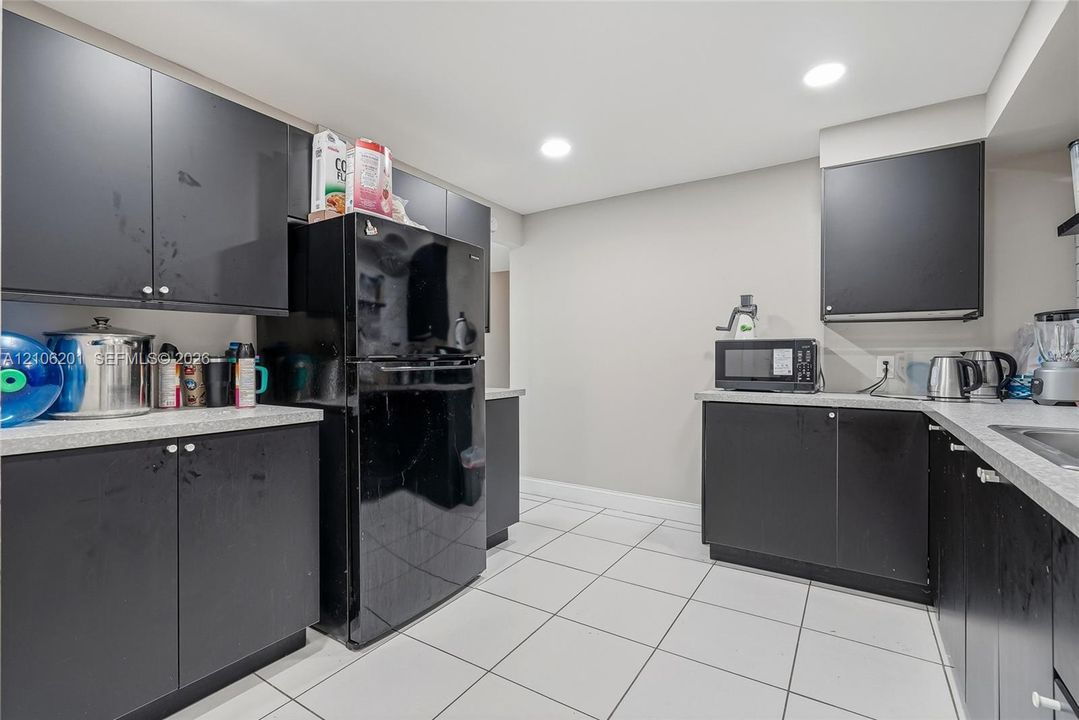 Kitchen featuring matte black cabinetry, light-toned composite countertops, white ceramic tile flooring, and recessed ceiling lighting