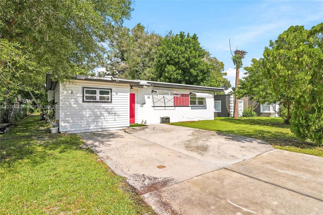 Single-story residence featuring white horizontal siding, a bright red front door, and a concrete driveway
