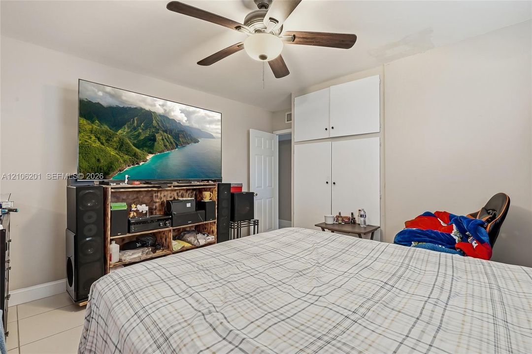 Room featuring a ceiling fan with integrated lighting and built-in floor-to-ceiling cabinetry with overhead storage