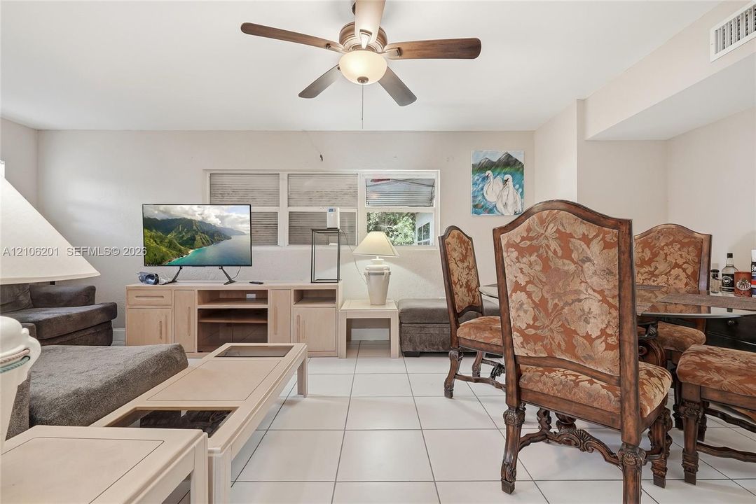 Ceramic tile flooring, built-in light-toned cabinetry, multi-pane window configuration, and a central ceiling fan with an integrated light fixture