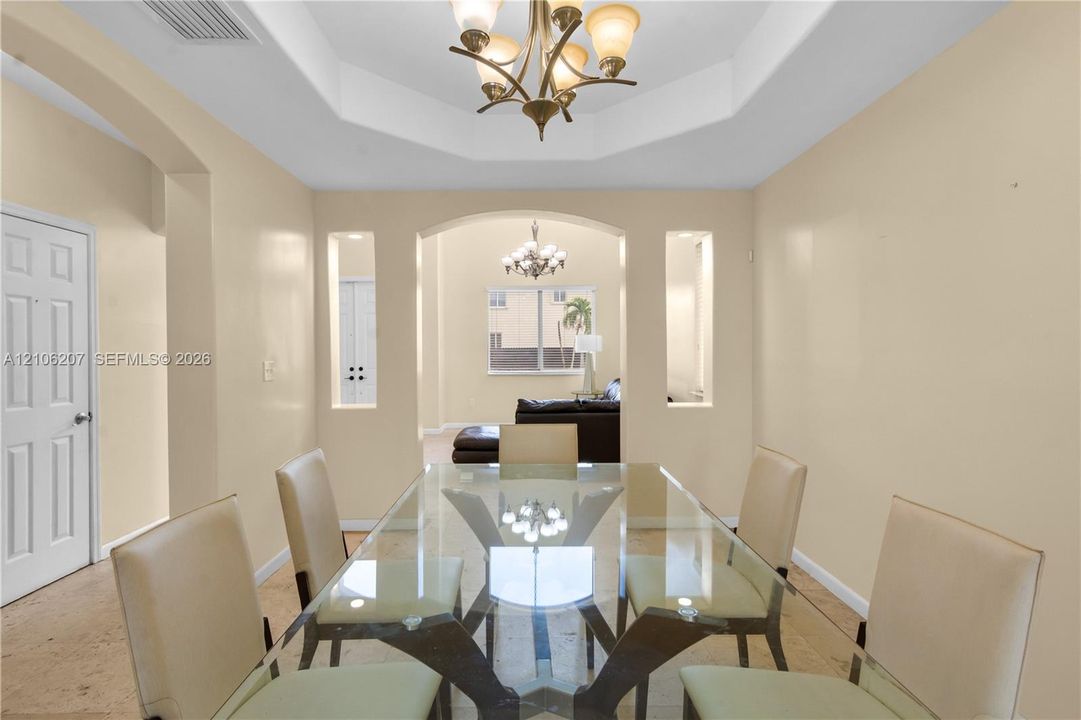 Dining space featuring a tiered tray ceiling, recessed wall niches, tile flooring, and an ornamental chandelier