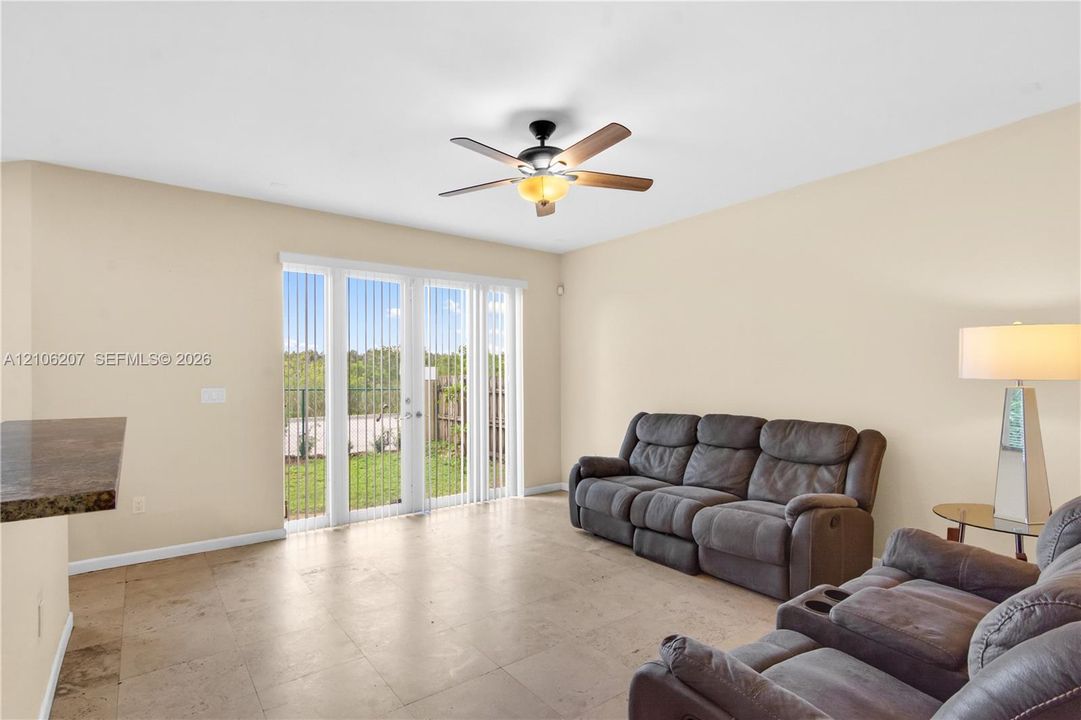 Large-format tile flooring, ceiling fan with integrated lighting, and glass sliding doors