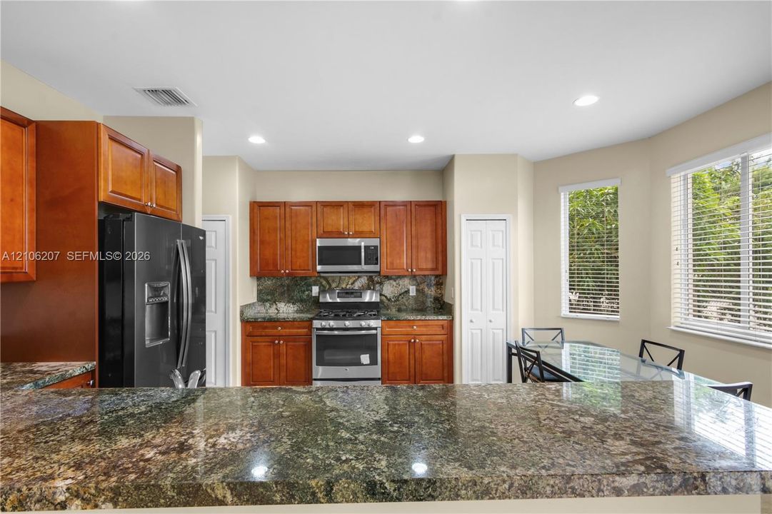 Kitchen featuring stained wood cabinetry, stone-surface breakfast bar, stainless steel appliances, and natural lighting