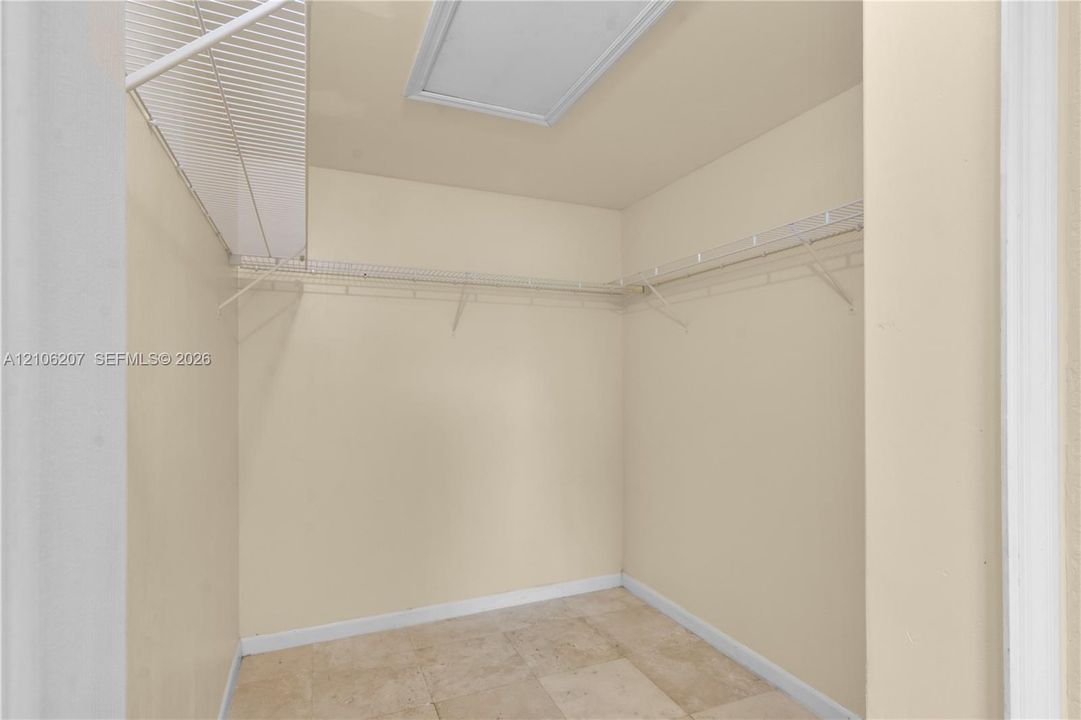 Storage area featuring tile flooring, white wire shelving, and an integrated ceiling access panel