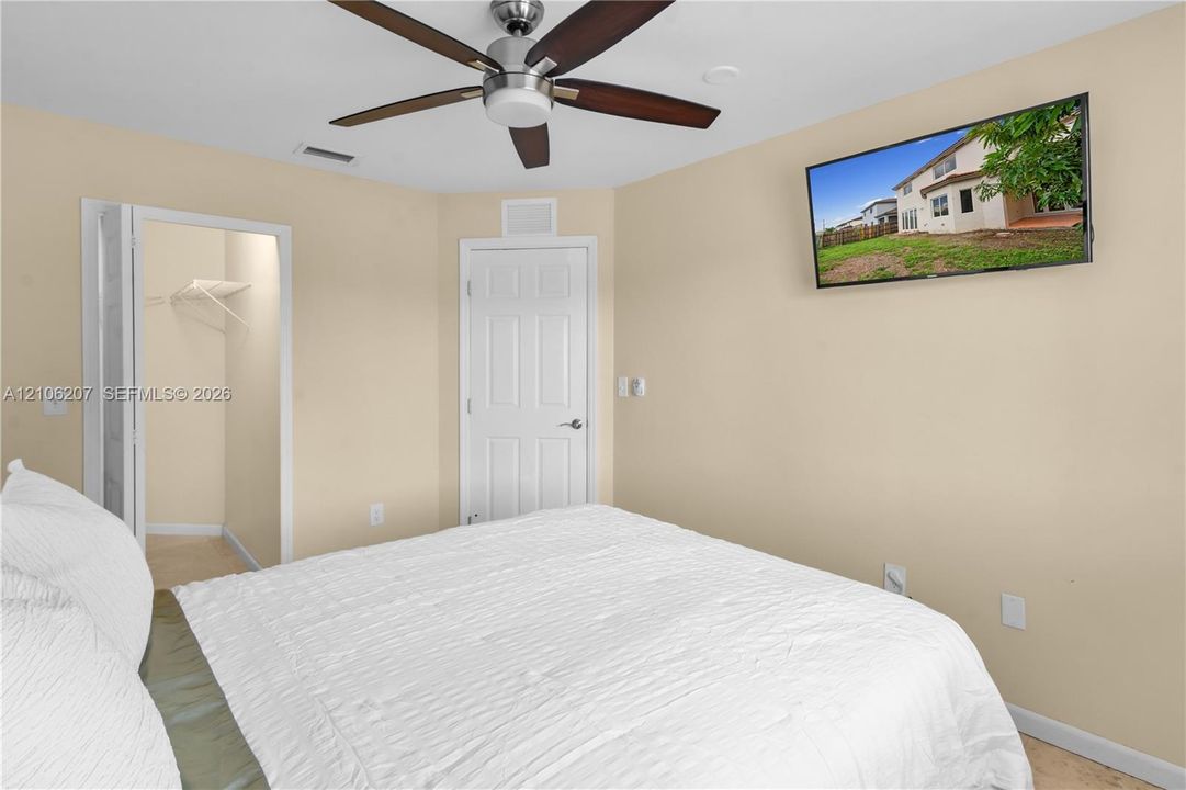Neutral interior featuring a ceiling fan with integrated lighting, a walk-in closet, and a multi-panel interior door