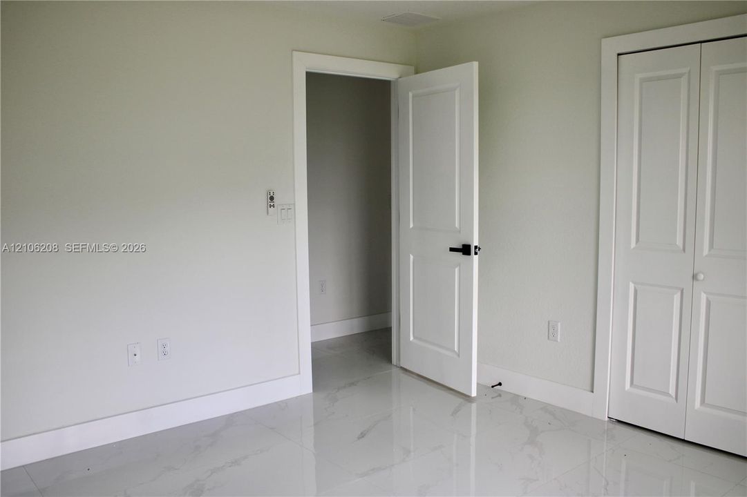 Interior room featuring polished stone-finish tile flooring, white two-panel interior doors, and matte black hardware