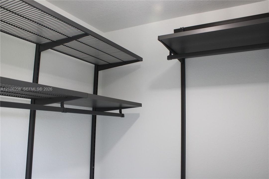 Customizable dark-finish metal shelving system featuring tiered wire racking and integrated hanging rods