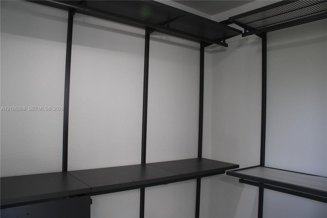 Custom closet organization system featuring black metal framing, tiered shelving, and integrated hanging rods