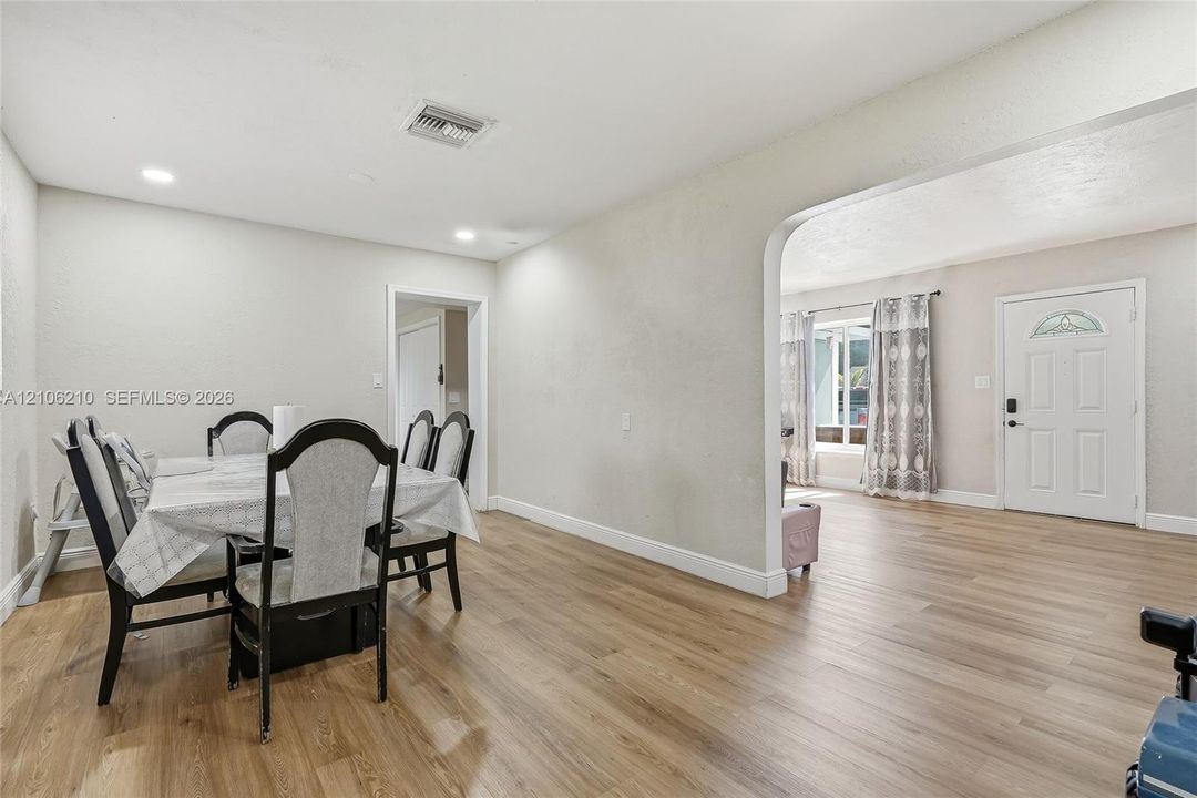 Open-concept interior featuring wood-finish flooring, recessed lighting, and a prominent arched entryway leading to the exterior entrance door