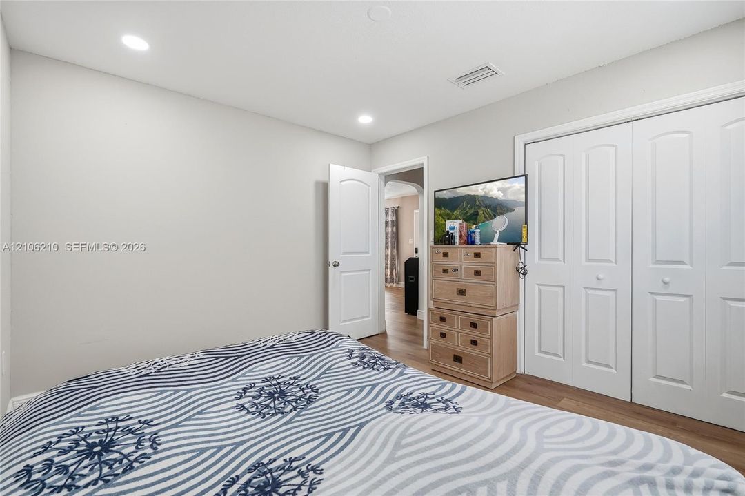 Neutral-toned interior featuring wood-finish flooring, recessed lighting, and double-panel closet doors