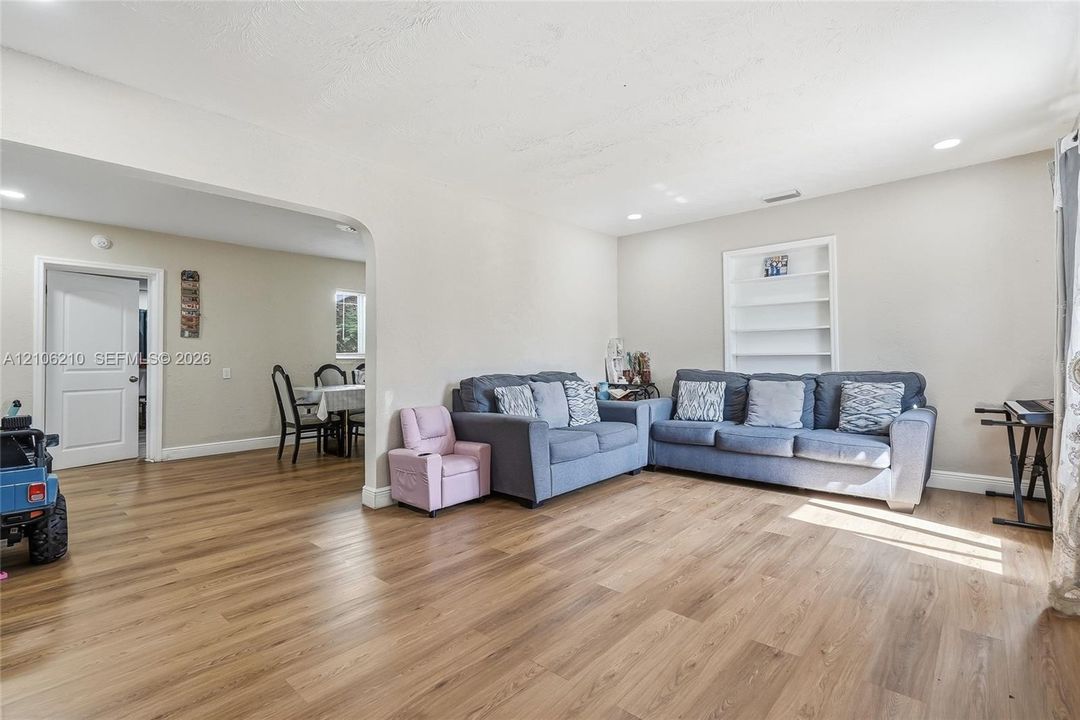 Open-concept interior featuring wood-finish flooring, recessed lighting, and a built-in recessed wall shelving unit