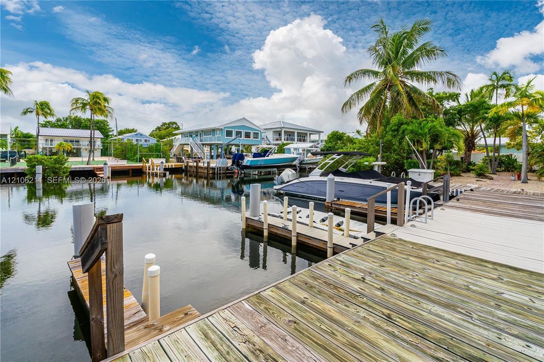 Deep-water canal frontage featuring a private wooden dock, concrete pilings, and direct bulkhead access
