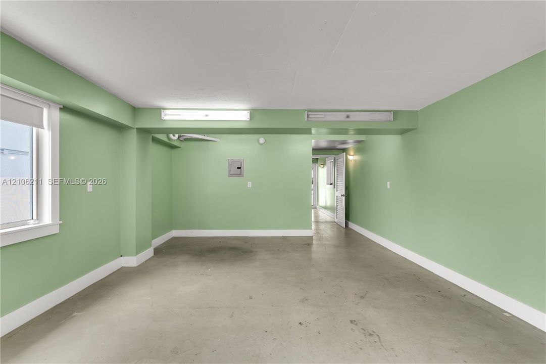 Multi-purpose interior space featuring smooth concrete flooring, overhead fluorescent lighting, and a single-pane window